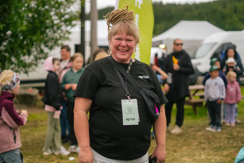 Smilende messevert med Agrisja-skilt rundt halsen