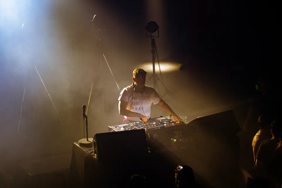 DJ bak miksepulten i røyk og motlys